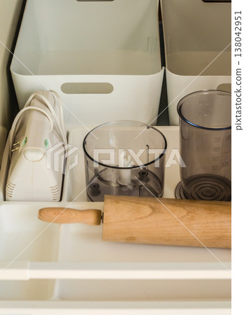 Neatly organized kitchen drawer with baking tools, appliances, and white storage containers. Home organization concept. 138042951
