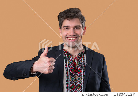 Ukrainian businessman in vyshyvanka with thumbs up, approval - like on beige 138043127