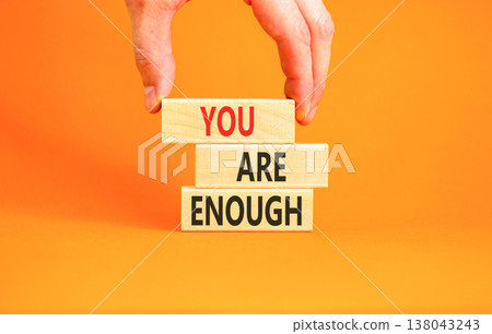 You are enough words symbol. Concept words You are enough on beautiful wooden blocks. Beautiful orange background. Businessman hand. Business motivational and you are enough concept. Copy space. 138043243