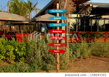 La Mer in Dubai, UAE - May 06, 2018: Signpost on the beach of La Mer at sunset. It is a new beachfront district with shopping and restaurants in Jumeirah. DUBAI, UAE -May 06, 2018 . La Mer in Dubai, UAE - May 06, 2018: Signpost on the beach of La Mer at sunset. It is a new beachfront district with shopping and restaurants in Jumeirah. DUBAI, UAE -May 06, 2018 . 138043391
