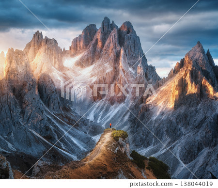 Girl on the mountain peak and amazing high rocks at sunset Girl on the mountain peak and amazing high rocks at sunset 138044019