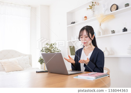 一位二十多歲的女性正在參加線上會議，對著電腦講話。 138044363