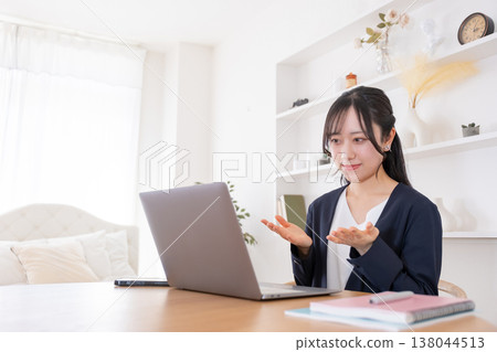 A woman in her 20s speaking into her computer during an online meeting. A woman in her 20s speaking into her computer during an online meeting. 138044513