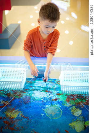 Happy boy scooping fish with a small net Happy boy scooping fish with a small net 138044583