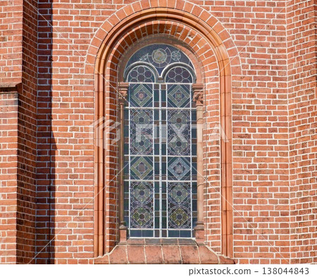 Neogothic Leaded Glass Window in a Red Brick Wall of a Historic Church. Neogothic Leaded Glass Window in a Red Brick Wall of a Historic Church. 138044843