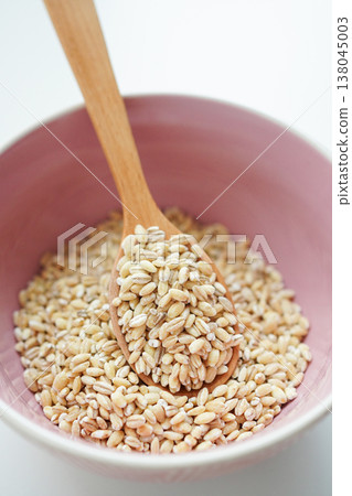 Image of healthy food: Pearl barley (polished pearl barley) and a wooden spoon stand out against a white background. Image of healthy food: Pearl barley (polished pearl barley) and a wooden spoon stand out against a white background. 138045003
