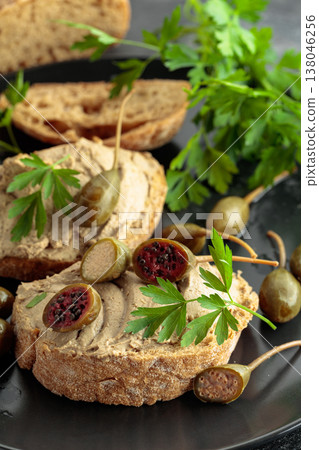 Bread with liver pate, capers, and fresh parsley. 138046256