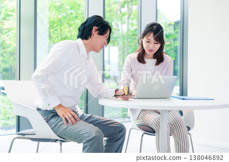 A boss holds a meeting with his female subordinate while eating rice balls. 138046892