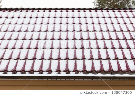 Red tiled roof partially covered with fresh snow Red tiled roof partially covered with fresh snow 138047300