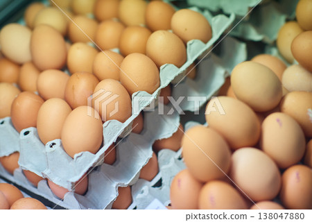 Stacked brown eggs in cardboard cartons at a market, fresh farm produce for cooking and baking 138047880