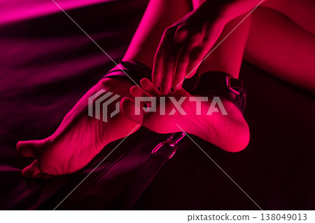 Women's legs in leather shackles. BDSM fetish. Women's legs in leather shackles. BDSM fetish. 138049013