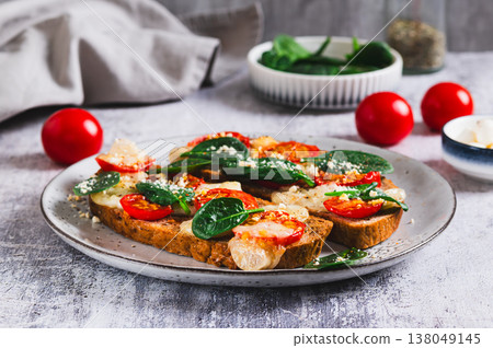Baked sandwiches with mozzarella, tomatoes and spinach on a plate on the table Baked sandwiches with mozzarella, tomatoes and spinach on a plate on the table 138049145