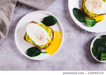 Rye bread with guacamole and poached egg on a plate on the table top view 138049159