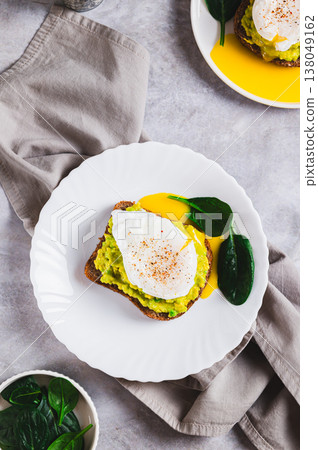 Avocado sandwich with poached egg and spinach on a plate top and vertical view 138049162