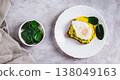 Avocado sandwich with poached egg and spinach on a plate top view web banner 138049163