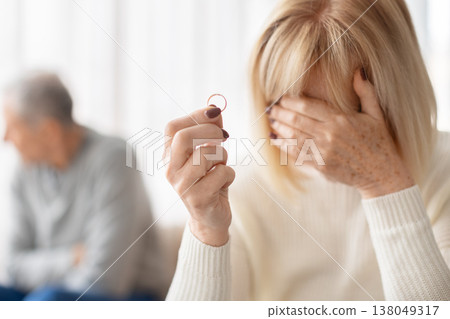 Closeup of senior woman holding wedding ring while crying and covering face Closeup of senior woman holding wedding ring while crying and covering face 138049317