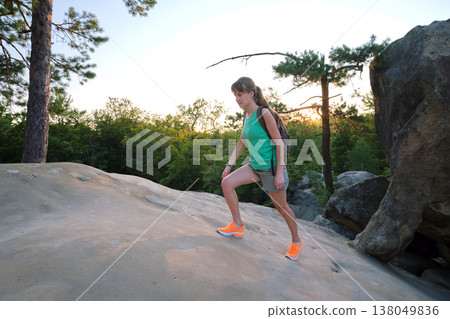 Young woman hiking alone on mountain footpath. Female hiker enjoying view of evening nature on wilderness trail. Active way of life concept 138049836
