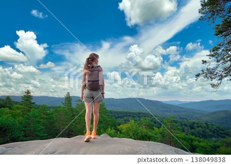 Young woman hiker standing alone on mountain footpath enjoying view of summer nature on wilderness trail. Active way of life concept 138049838