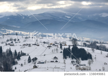 Winter landscape with small rural houses in remote settlement between snow covered forest in cold mountains Winter landscape with small rural houses in remote settlement between snow covered forest in cold mountains 138049861