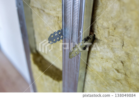 Wall of a room under renovation with mineral rock wool insulation and metal frame prepared for drywall plates. 138049884