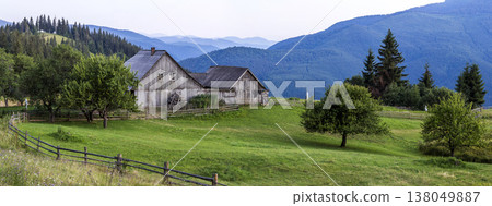Village houses on hills with green meadows in summer day. House of shepherds in mountains in carpathian Village houses on hills with green meadows in summer day. House of shepherds in mountains in carpathian 138049887