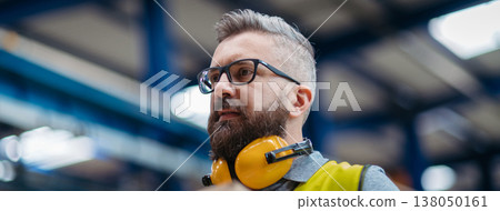 Warehouse or factory worker with protective earmuffs. Warehouse or factory worker with protective earmuffs. 138050161