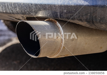 A car's exhaust pipe is dirty and has buildup. This is seen in a parking lot under natural light A car's exhaust pipe is dirty and has buildup. This is seen in a parking lot under natural light 138050856
