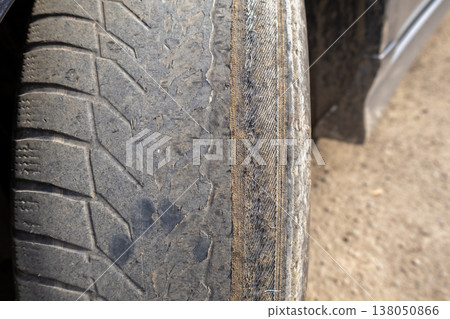 A person is wiping down the dirty wheel of a car to maintain its condition and prevent damage while parked outside 138050866