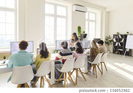 Programming lesson for teen students with teacher at computers in modern classroom 138052982