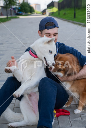 A man hugs his two dogs while on a walk. A man hugs his two dogs while on a walk. 138053020