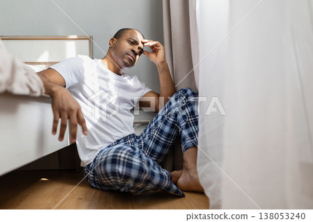 Young black man sitting on floor, holding head in frustration and stress 138053240