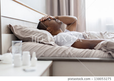 Young black man lying in bed holding head in pain Young black man lying in bed holding head in pain 138053275