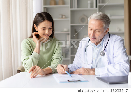 Pregnant woman reviewing medical paperwork with doctor during prenatal consultation Pregnant woman reviewing medical paperwork with doctor during prenatal consultation 138053347