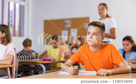 Portrait of schoolboy who writing exercises at lesson in primary school Portrait of schoolboy who writing exercises at lesson in primary school 138053693