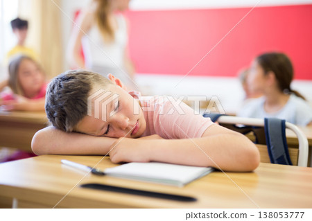 Tired school boy sleeping in classroom during lesson 138053777