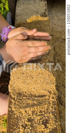 Children's hands playing with sand on a wooden surface Children's hands playing with sand on a wooden surface 138053802