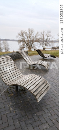 wooden benches in the form of sun loungers on the site overlooking the lake 138053805