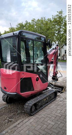 Compact red mini excavator at construction site on city street Compact red mini excavator at construction site on city street 138053832