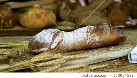 Freshly baked bread on a wooden board with wheat and other types of bread in a bakery setting Freshly baked bread on a wooden board with wheat and other types of bread in a bakery setting 138054581