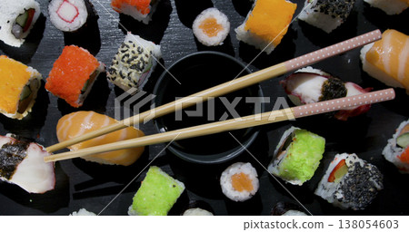 Colorful sushi on a black plate with chopsticks and soy sauce during a meal in a dining setting 138054603