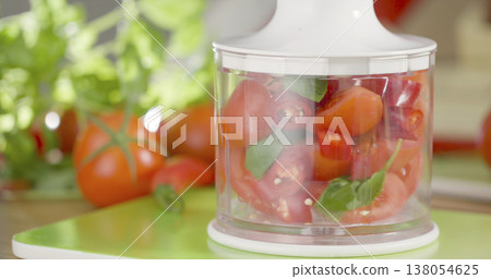 Chopping tomatoes and herbs in a kitchen with fresh ingredients and tools for meal preparation Chopping tomatoes and herbs in a kitchen with fresh ingredients and tools for meal preparation 138054625
