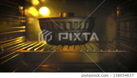 Baking process in an oven with a black placed on the rack and warm light illuminating the scene during evening hours Baking process in an oven with a black placed on the rack and warm light illuminating the scene during evening hours 138054637