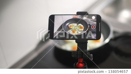 Cooking eggs in a frying pan while recording a video in a kitchen setting during the day Cooking eggs in a frying pan while recording a video in a kitchen setting during the day 138054657