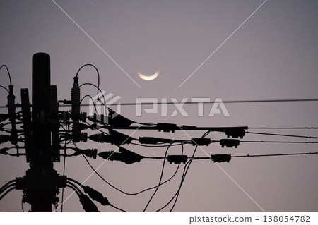 A landscape featuring a crescent-shaped moon and utility poles. 138054782