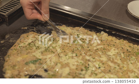 東京市中心美食街上,鐵板上正在烹調文字燒。 東京市中心美食街上,鐵板上正在烹調文字燒。 138055410