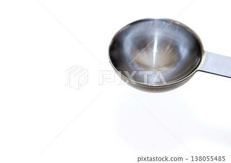 一把裝滿清澈液體的金屬勺子 一把裝滿清澈液體的金屬勺子 138055485