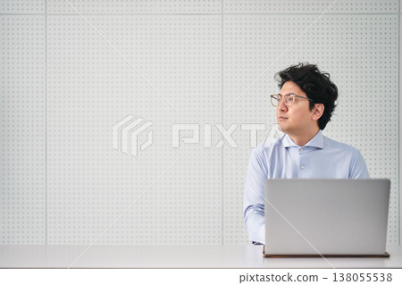 一位三十多歲、戴著眼鏡的公司職員,正在室內操作電腦。 一位三十多歲、戴著眼鏡的公司職員,正在室內操作電腦。 138055538