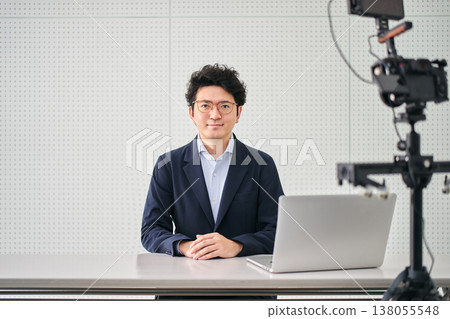 A male news anchor looking directly at the camera while filming the news in a studio. A male news anchor looking directly at the camera while filming the news in a studio. 138055548