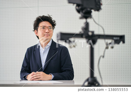 A news anchor reading a news script to the camera inside a filming studio. A news anchor reading a news script to the camera inside a filming studio. 138055553