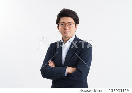一名三十多歲的男子,身穿西裝,自信地微笑著,雙手交叉抱在胸前,直視鏡頭。 一名三十多歲的男子,身穿西裝,自信地微笑著,雙手交叉抱在胸前,直視鏡頭。 138055559